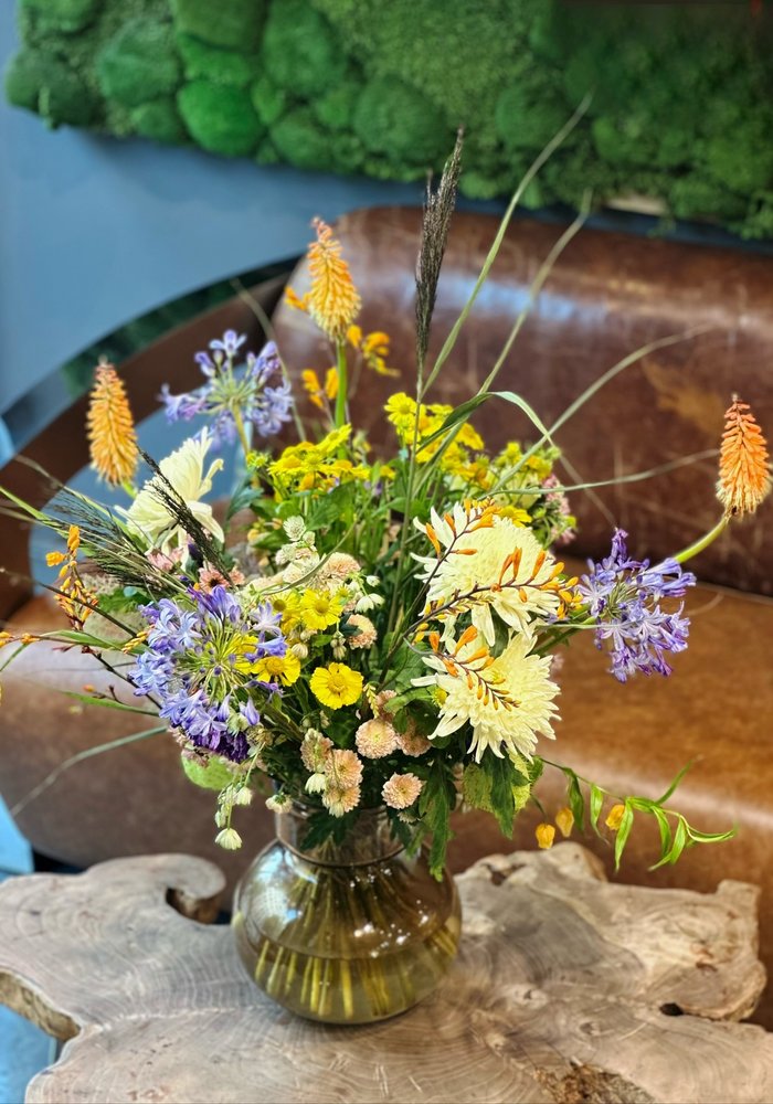 Bouquet in Gelb, Orange und Blau in einer Büro-Lounge mit Mooswand