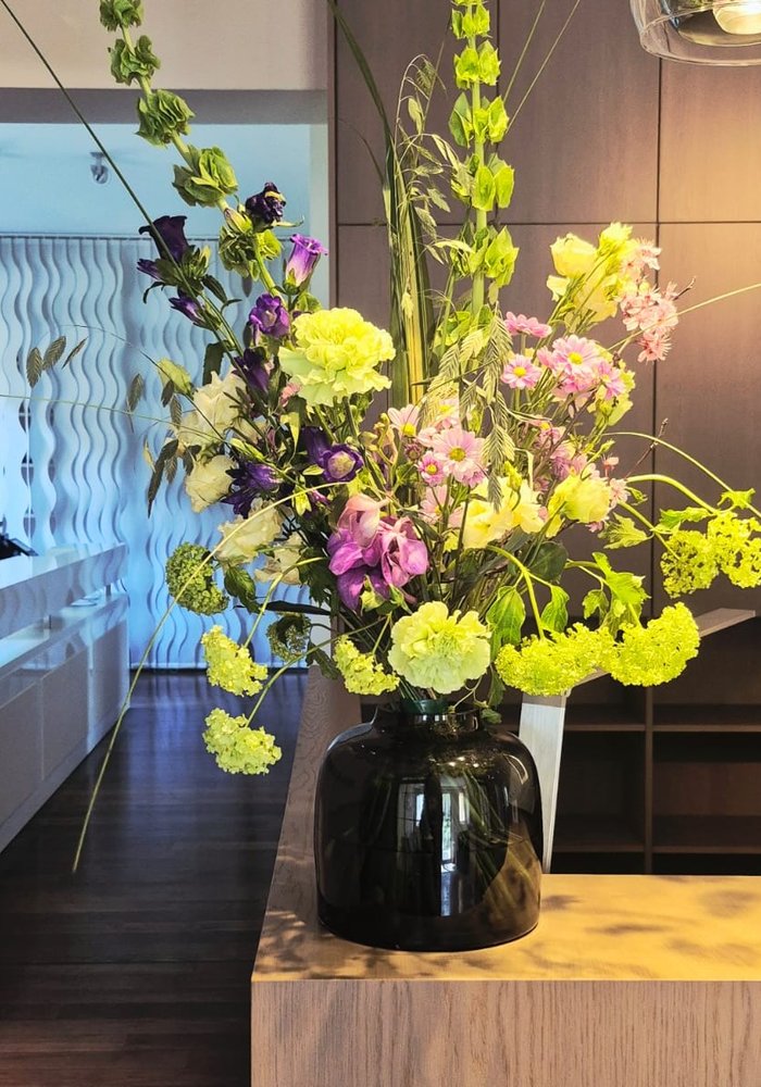 Hohe Komposition aus Nelken, Lisianthus und Muschelblumen in einer Lobby