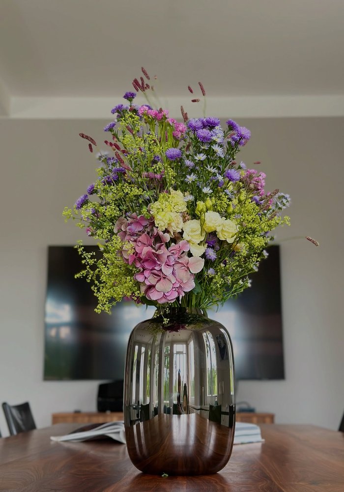 Bouquet mit rosa Hortensien und Wiesenblumen auf einem Esstisch aus Holz