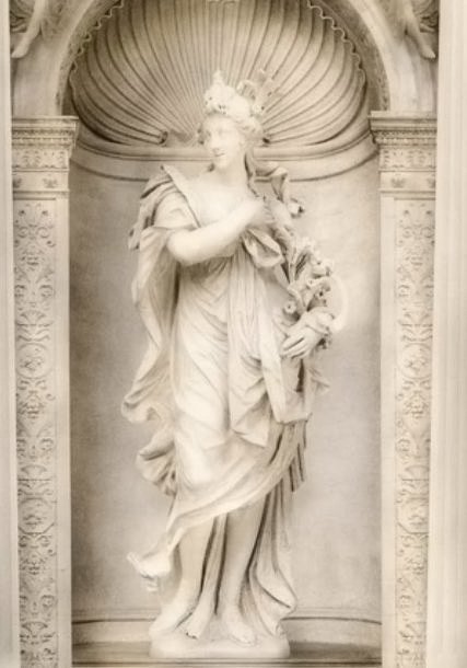 Statue of a woman holding an armful of lilies, in a shell niche of our wallpaper